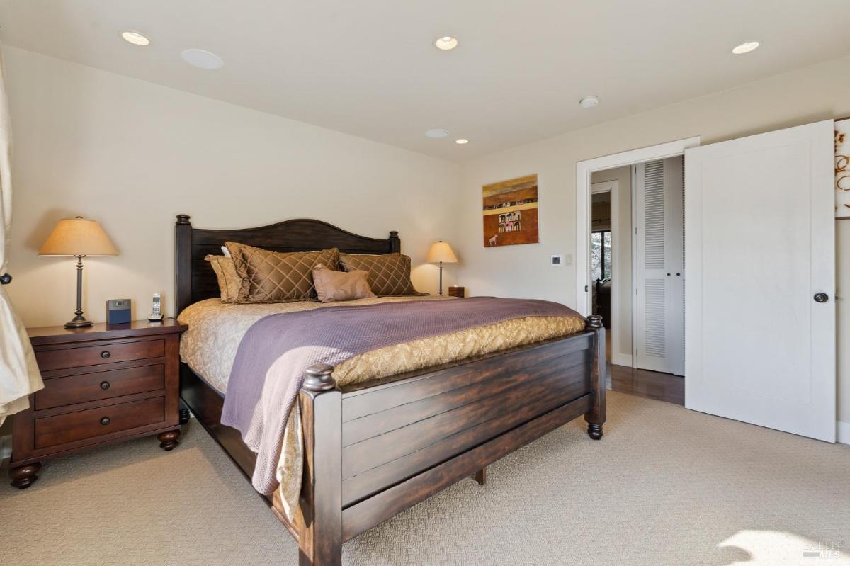 A bedroom with a large wooden bed and two side tables with lamps.