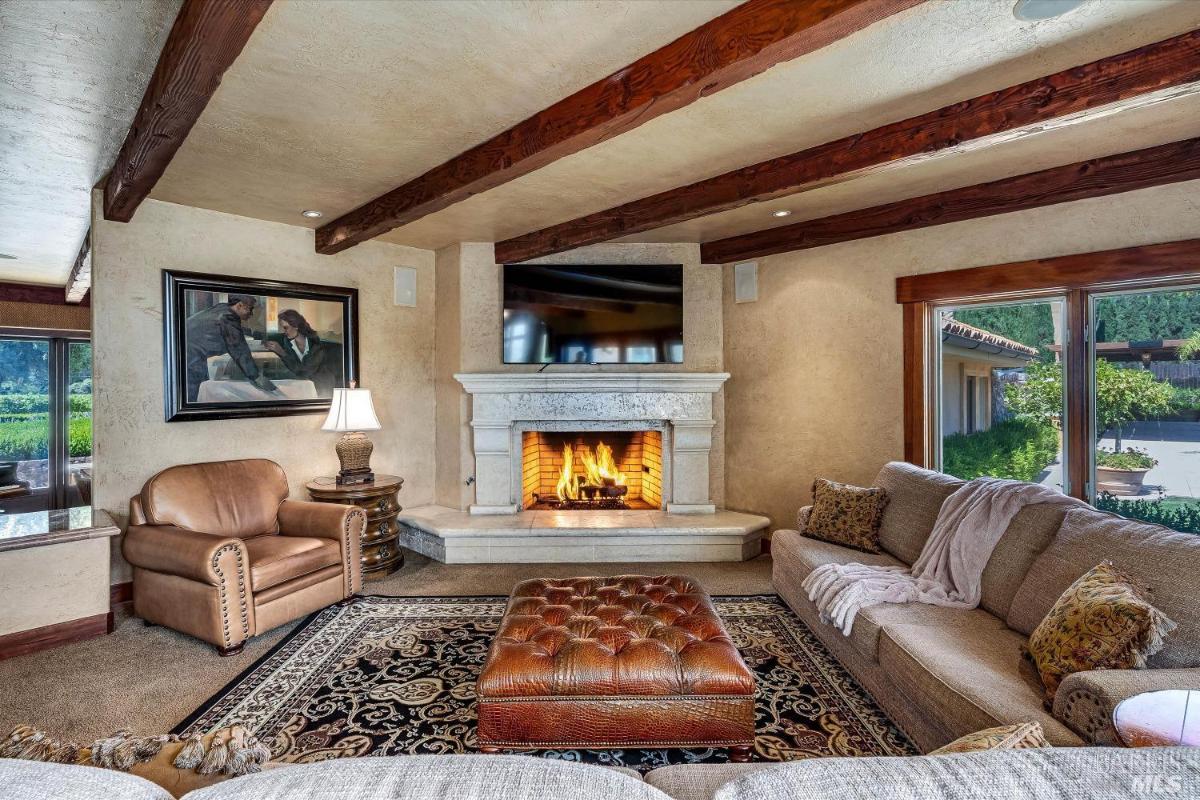 Family room with with a fireplace, a seating area, and exposed wooden beams.