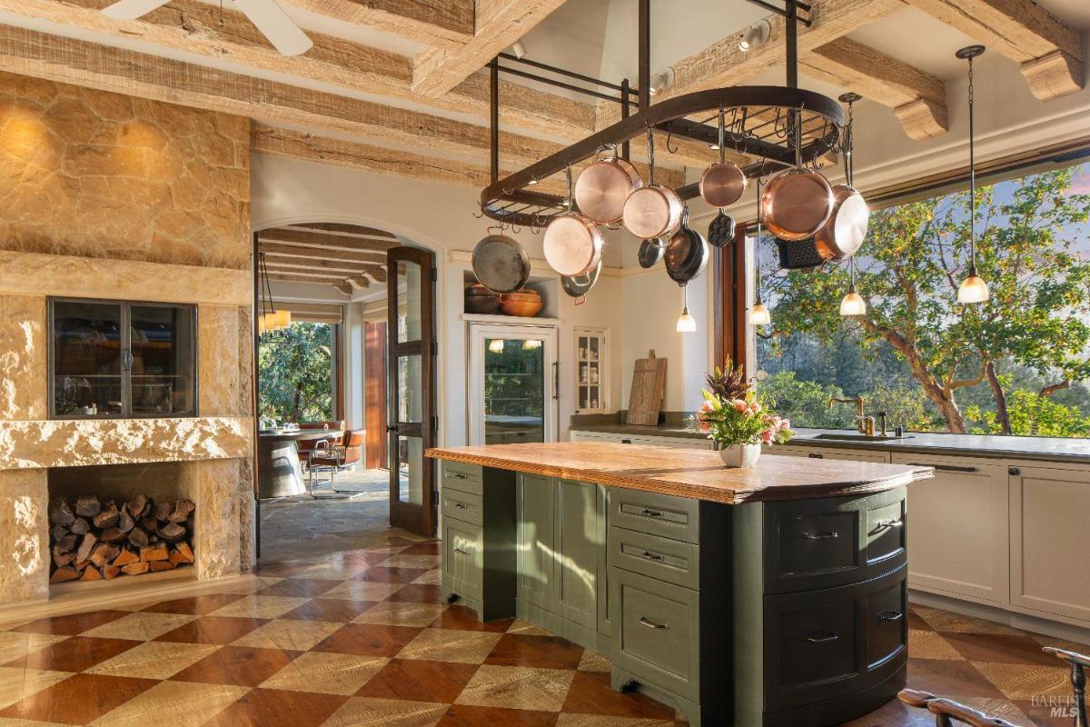 Another view of the kitchen showing a fireplace and access to adjacent spaces.