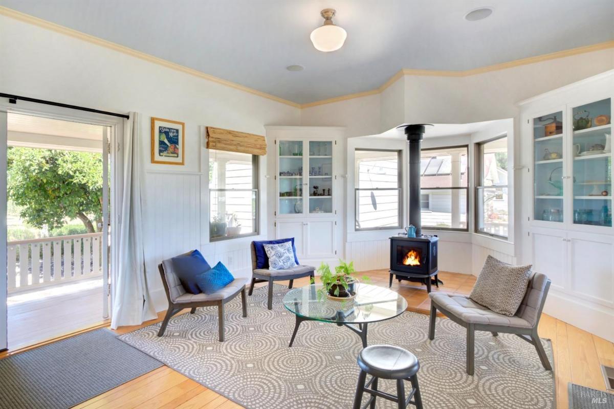 A seating area with a small wood-burning stove, chairs, and built-in cabinets, with a door leading to a porch.