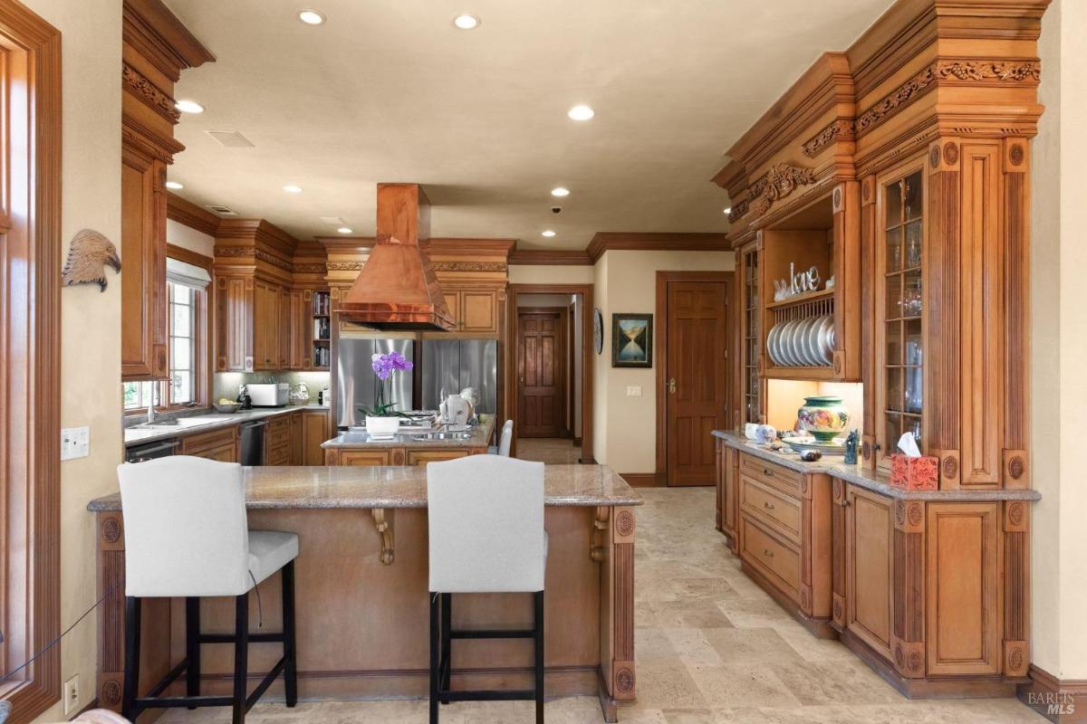 Kitchen features custom wood cabinetry, a central island, and a prominent copper range hood.