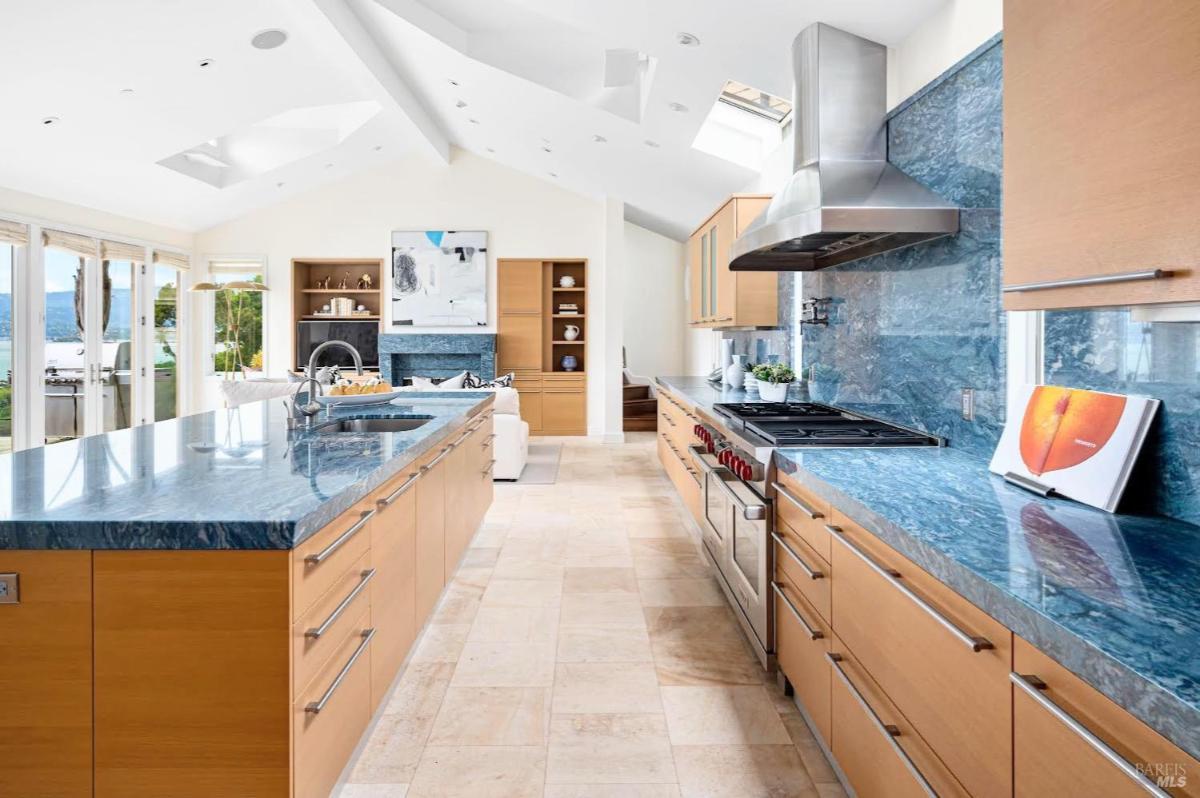 Kitchen featuring blue countertops, stainless steel appliances, and large windows.