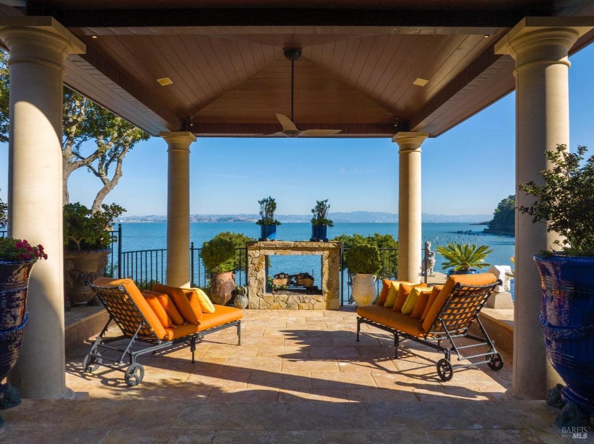 Covered patio with stone fireplace and sea views.