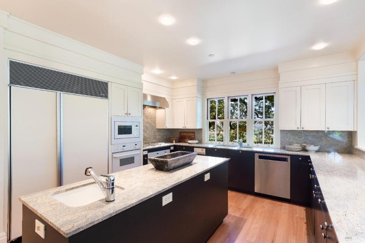 Kitchen with an island, granite countertops, and large windows.