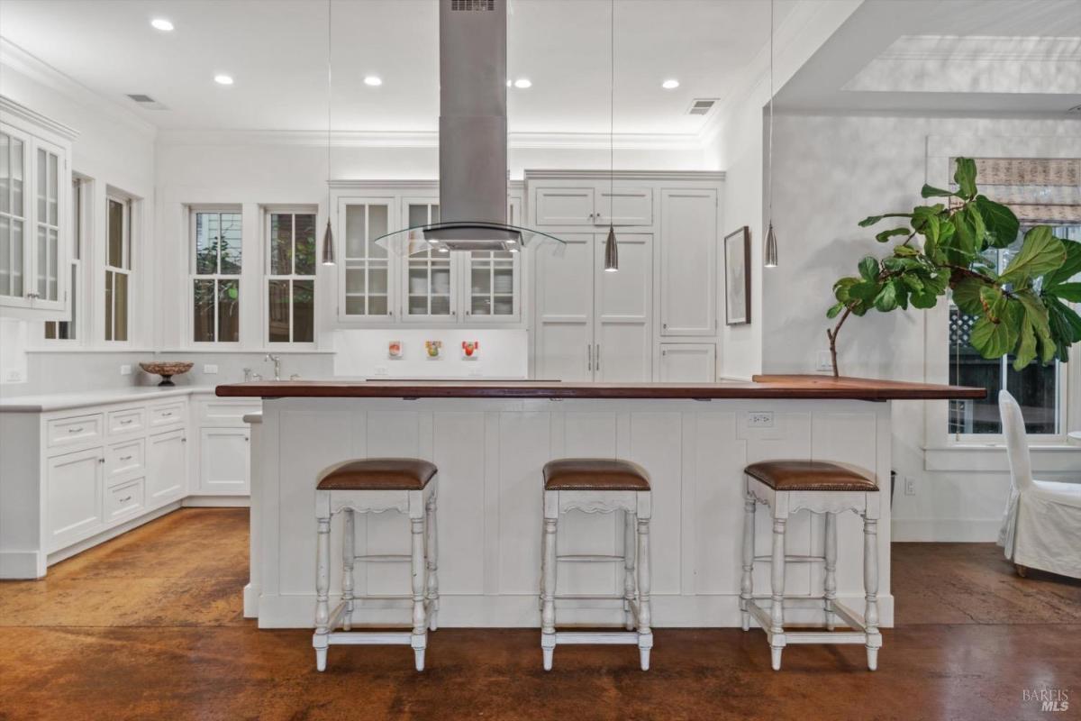 Kitchen with a white island, bar stools, and pendant lighting.