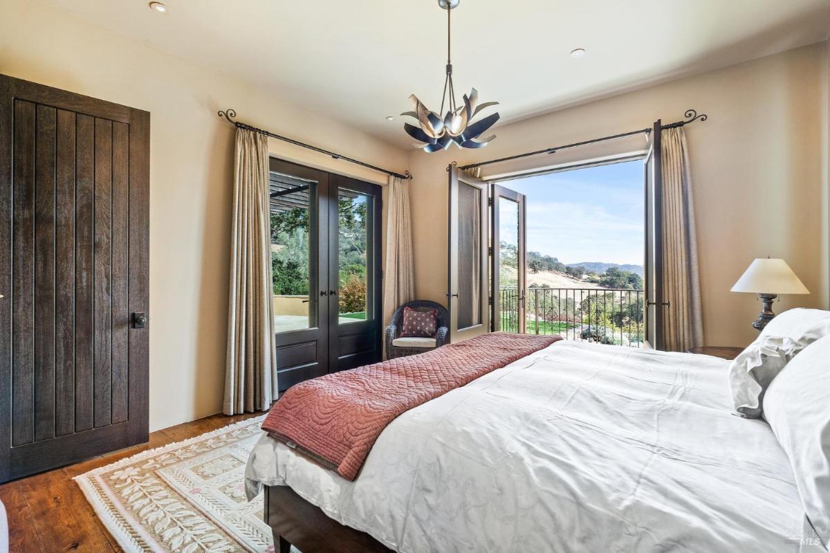 A bedroom with French doors opening to an outdoor view.