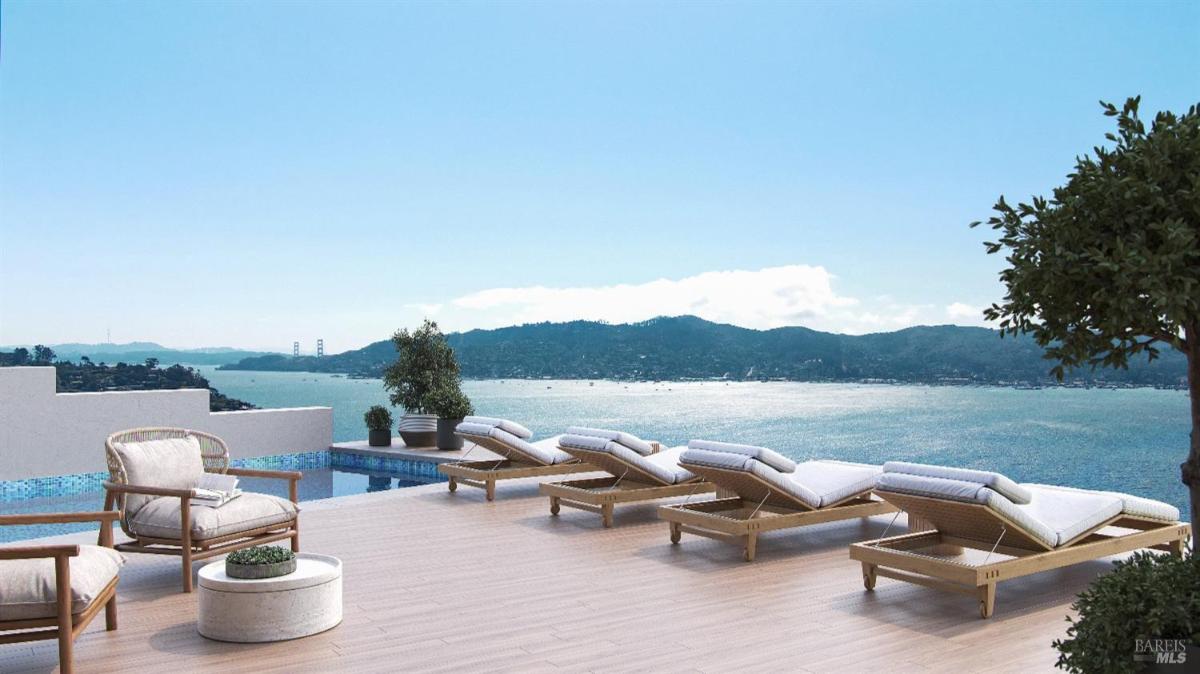 Outdoor area with lounge chairs and a table overlooking the swimming pool and mountains.