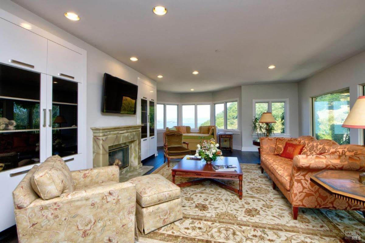 Family room featuring multiple seating arrangements, a fireplace, and windows providing panoramic outdoor views.