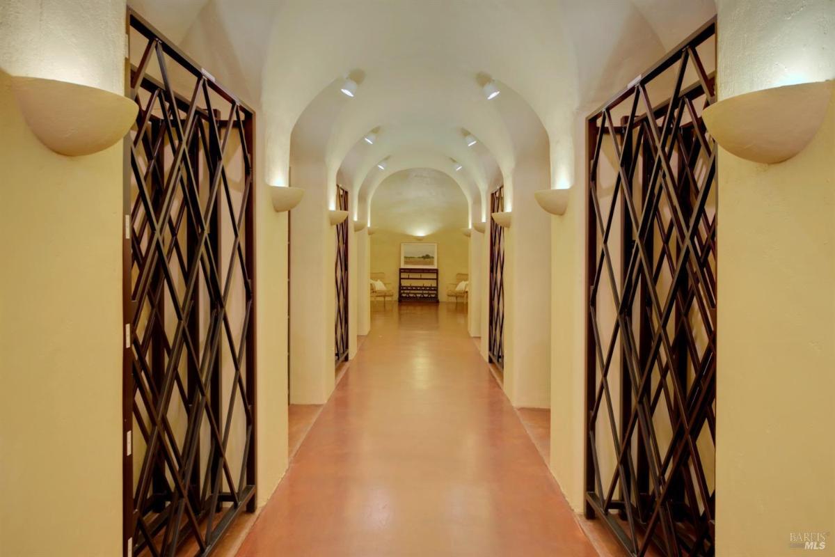 A view of a wine cellar corridor with archways and storage racks.