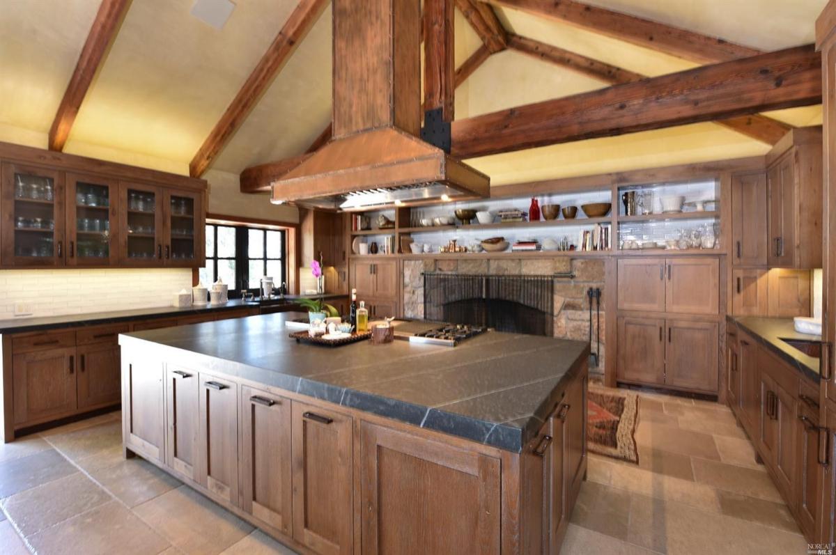 A kitchen with a stone backsplash, wooden cabinets, and a central island.