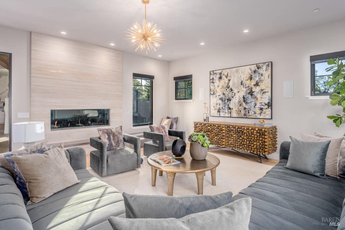 Living room featuring a modern fireplace, large artwork, wood console, velvet seating, and a round coffee table.