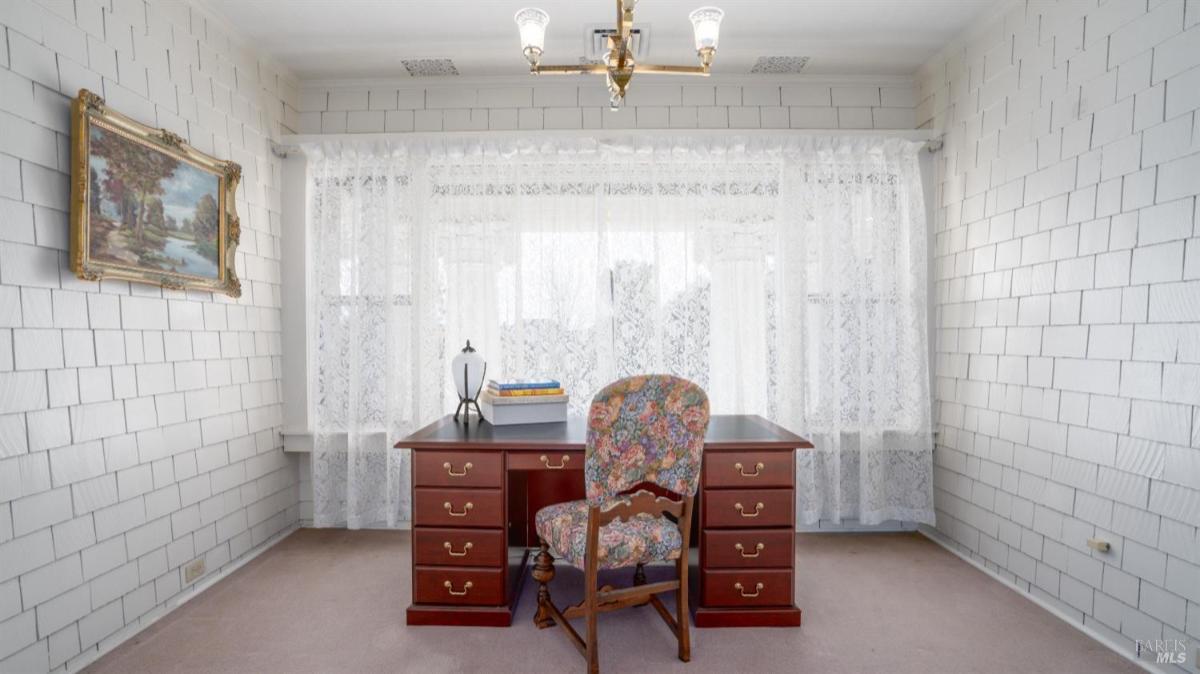 Small office room with a desk and lace curtains.