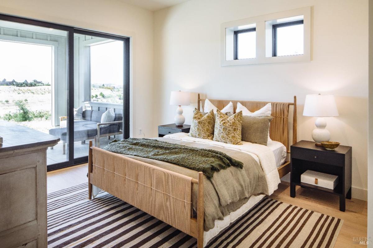 A bedroom with a bed, nightstands, and access to an outdoor area through sliding glass doors.