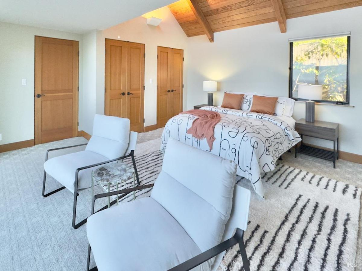 Bedroom with vaulted ceiling and seating area.