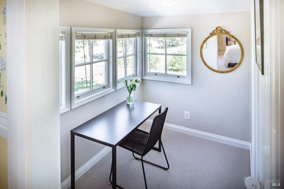 A small workspace with a desk, chair, and multiple windows.