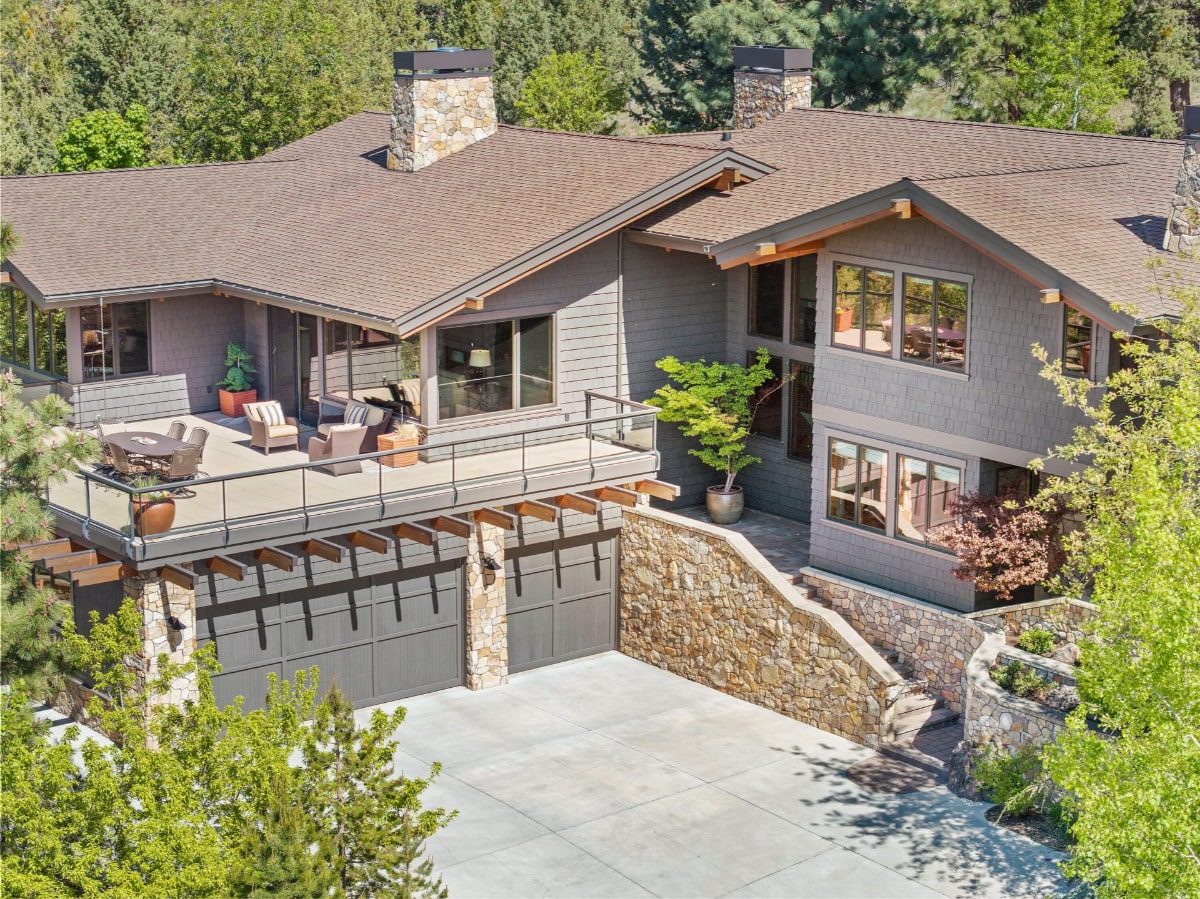 Aerial view of a large, modern house nestled in a wooded area.