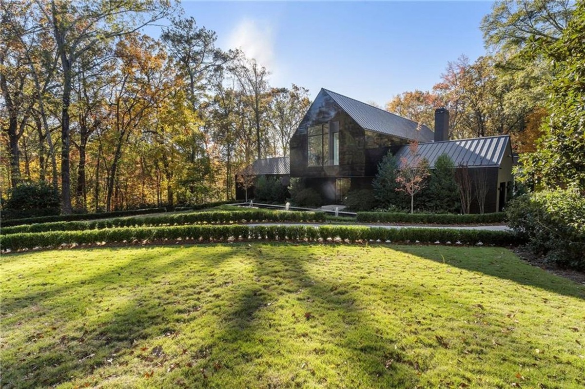 Mansion framed by a manicured lawn, vibrant autumn foliage, and modern architectural brilliance.