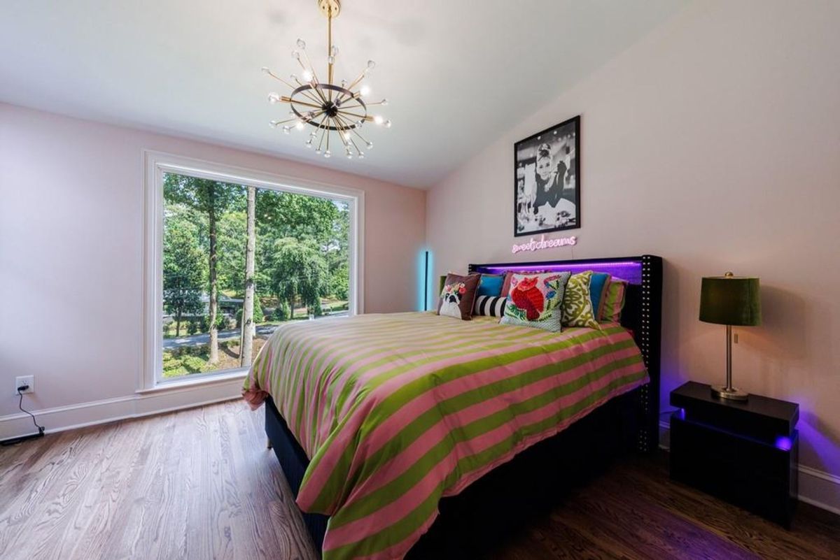 Bright bedroom features a striped comforter, a unique chandelier, and a vibrant headboard.