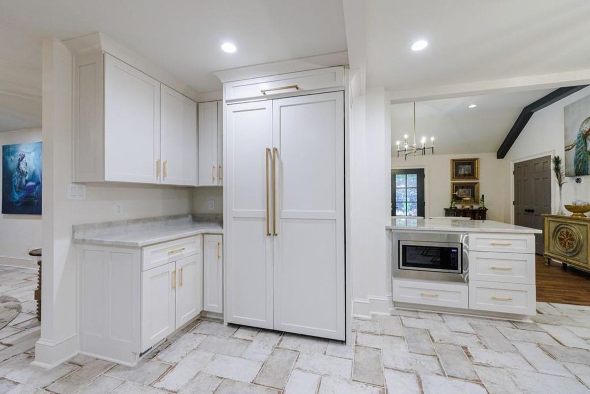 Elegant kitchen boasts a farmhouse sink, dark cabinetry, and stunning lantern lighting.