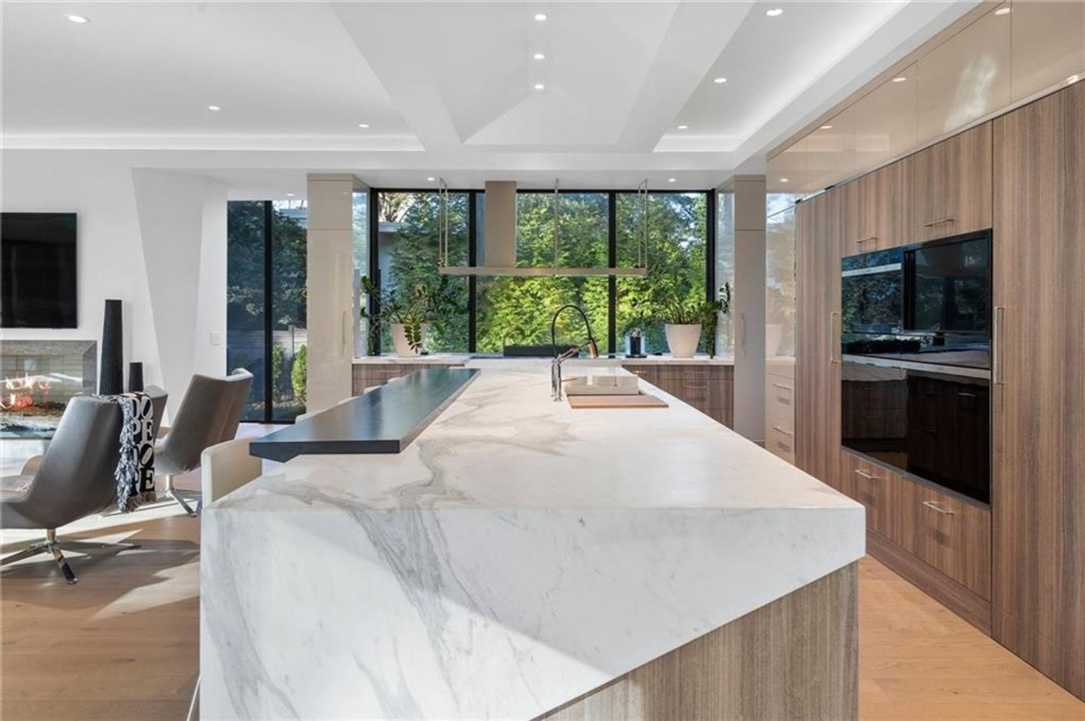 Open kitchen showcases a waterfall-edge marble island and seamless cabinetry.