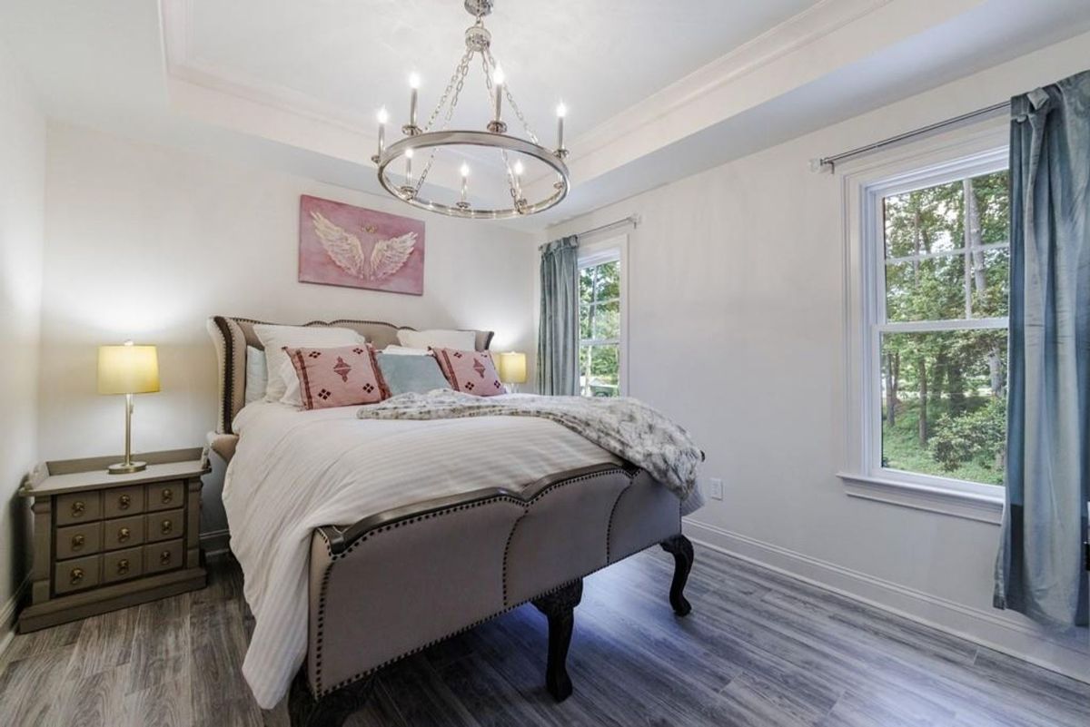 Peaceful bedroom showcases a large bed, a dramatic chandelier, and a serene color palette.