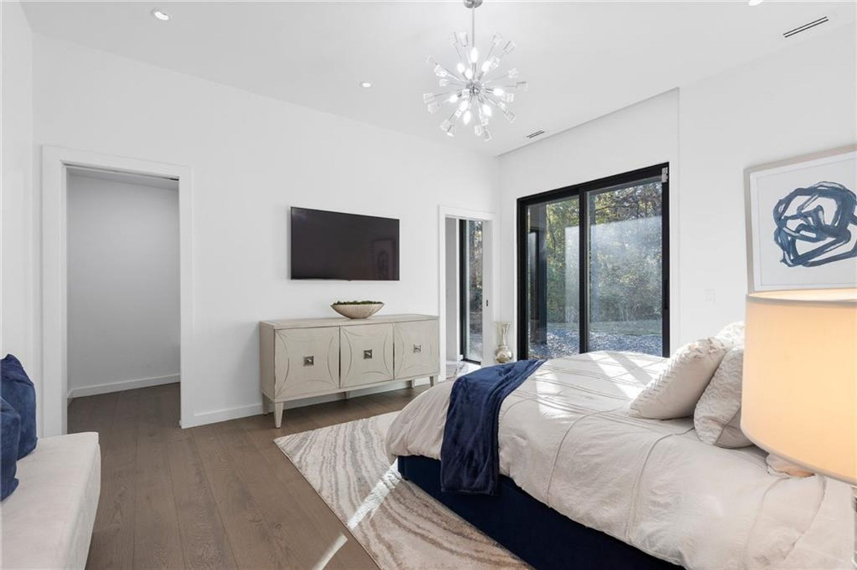 Guest suite offers a sleek design with bright white tones and stylish chandelier.