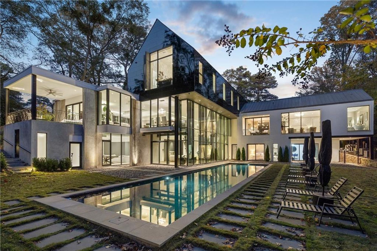 Glass-wrapped mansion reflecting elegance and tranquility, featuring a sleek lap pool and expansive terraces.