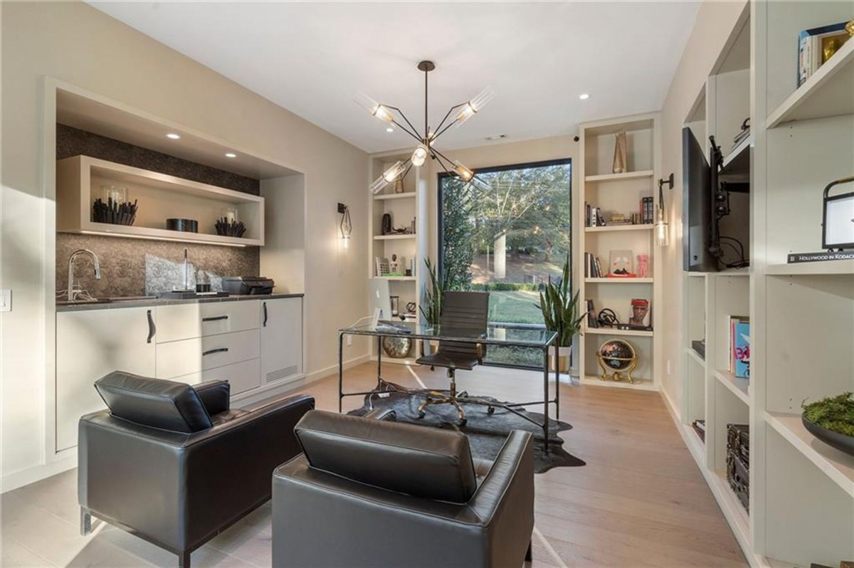 Home office exudes modern sophistication, featuring built-in shelves and a wet bar