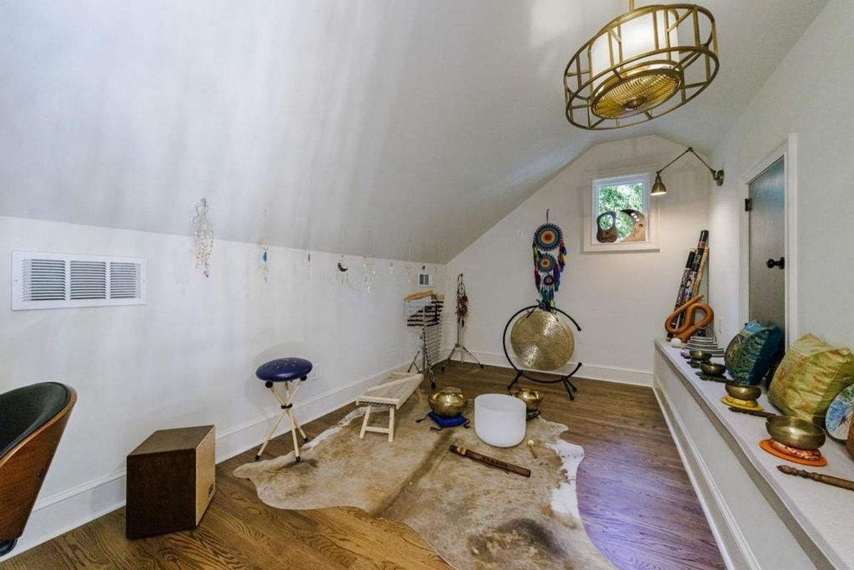 Unique attic space is set up as a meditation or sound healing room, featuring various instruments.