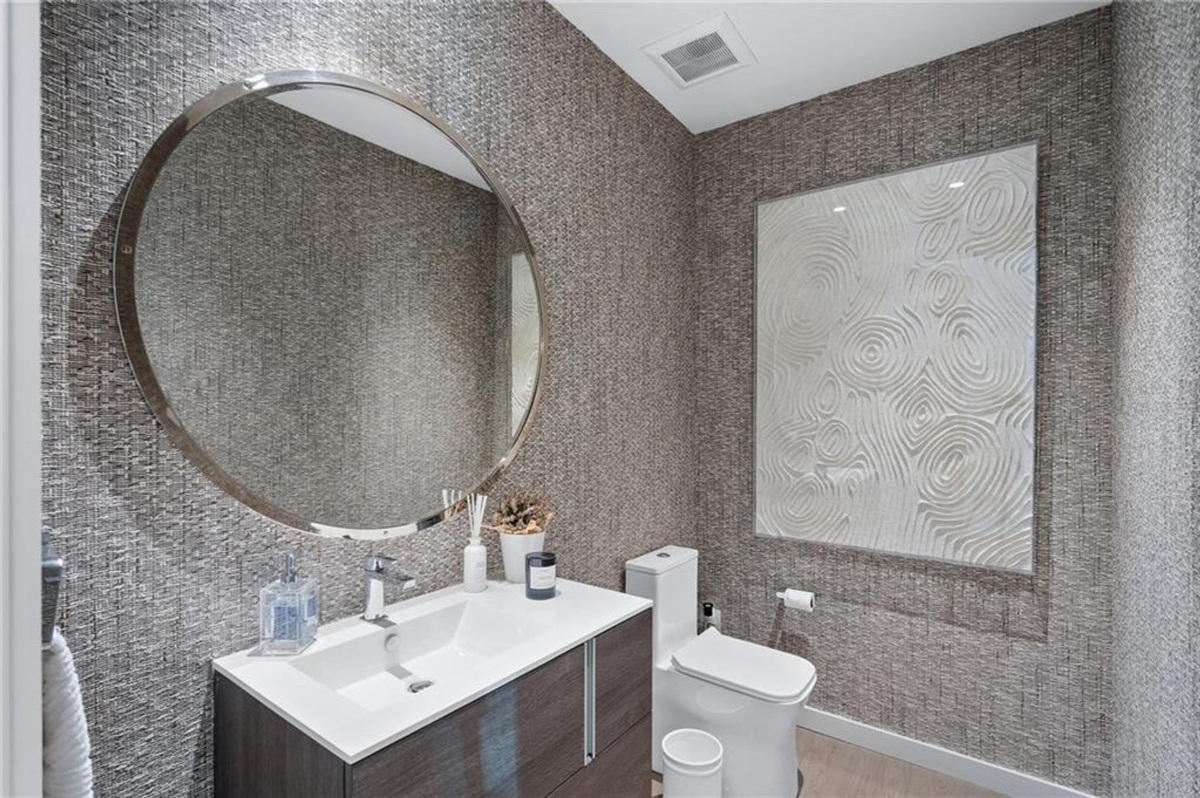 Powder room showcases textured walls and circular mirror.