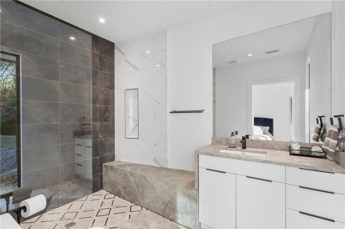 Bathroom combines modern tiling with a spacious walk-in shower and minimalist vanity design.