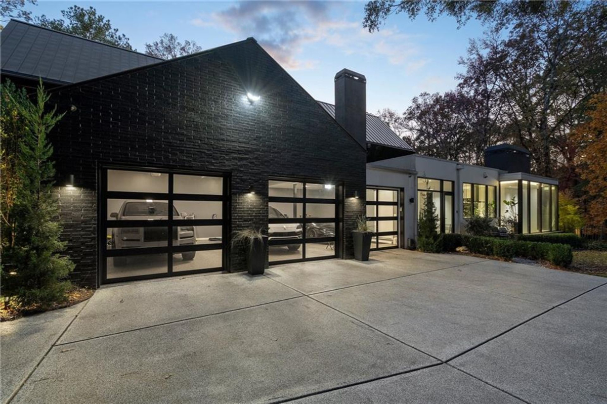 Garage design features sleek black brick with illuminated glass-paneled doors.