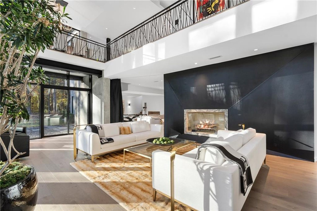 Modern living space highlighted by floor-to-ceiling windows and a striking black accent wall with a sleek fireplace.