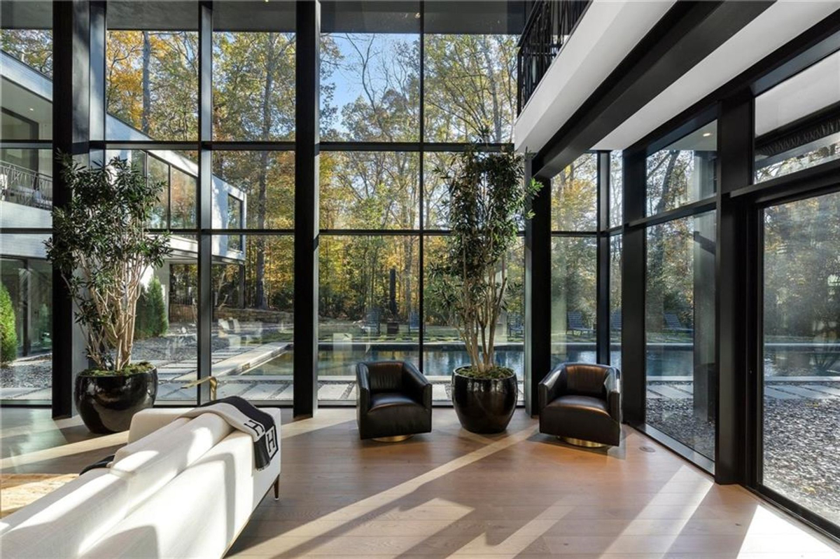 An inviting seating nook with floor-to-ceiling glass walls, offering seamless views of the serene outdoor landscape and reflecting pool.