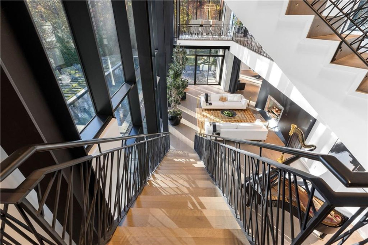 Staircase with sleek metal railings overlooks the expansive living room.