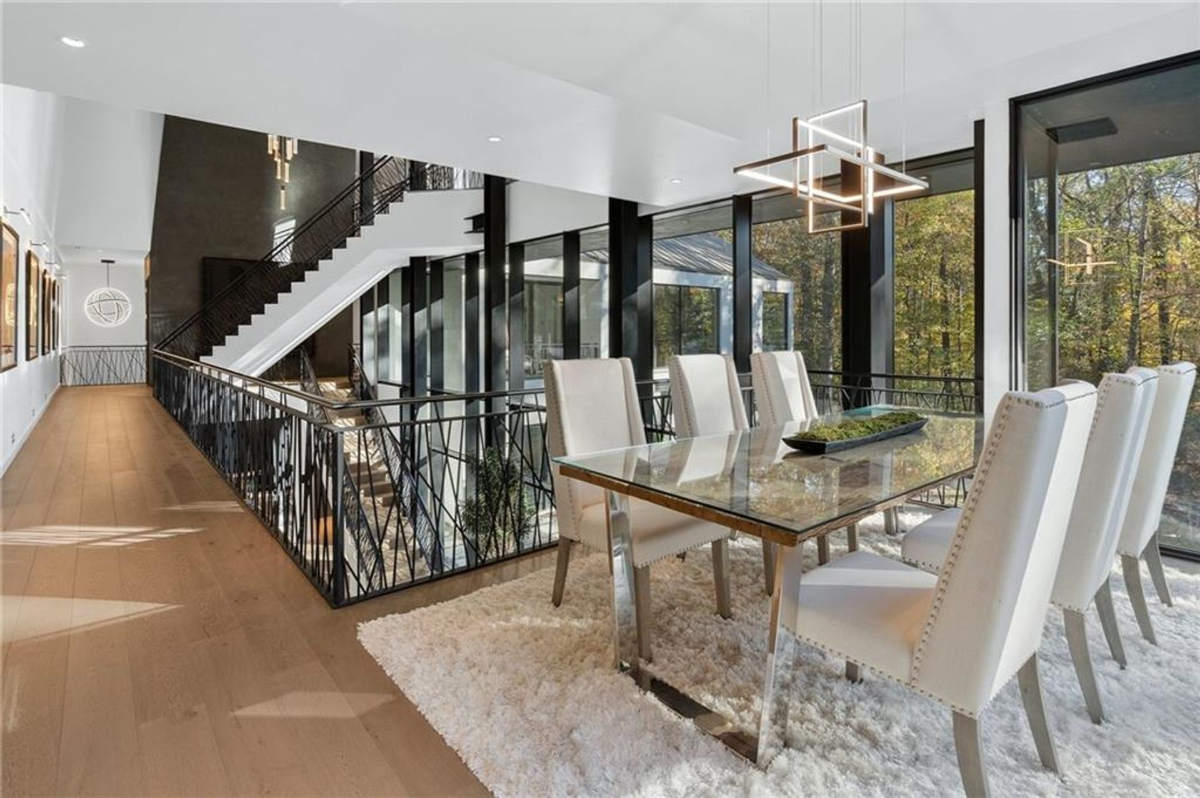 Dining area with a glass-top table overlooks scenic woodland views.