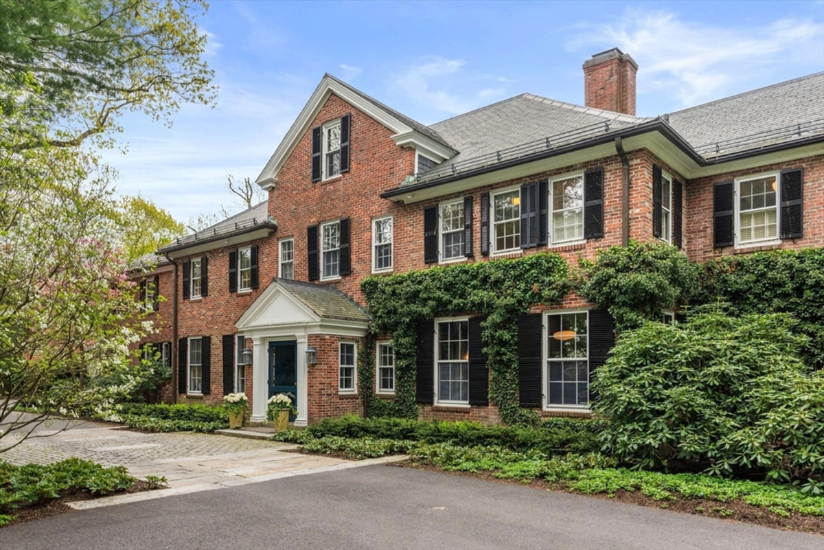 A grand Colonial facade adorned with ivy and complemented by a blue entrance door exudes classic sophistication.