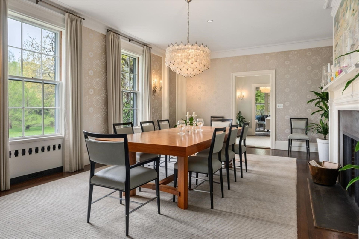 Dining room features a minimalist wooden table, contemporary chairs, and a shimmering chandelier that complements the serene wallpaper.