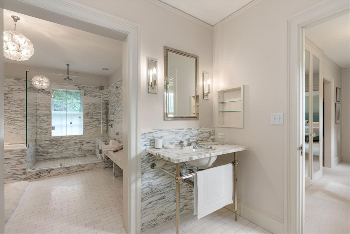 Bathroom combines marble accents with a spacious glass shower, modern vanity, and sleek lighting for a sophisticated ambiance.