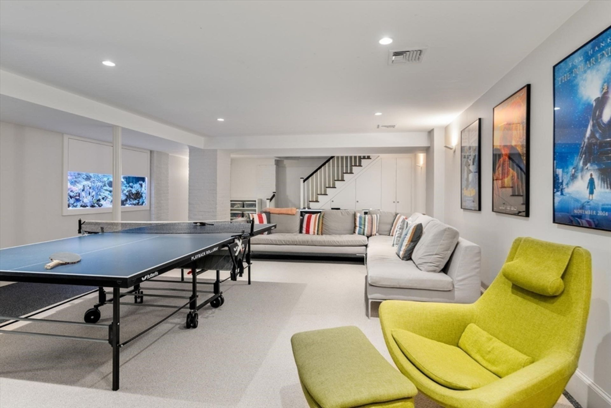 Basement recreation room offers space for entertainment with a ping pong table, plush sectional seating, and vibrant decor.