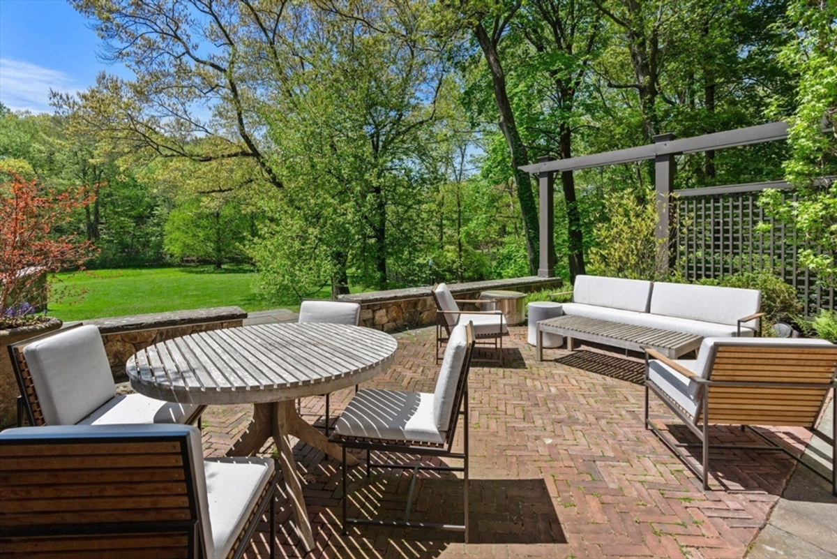 The patio blends elegant seating arrangements with lush greenery, offering a tranquil outdoor retreat.