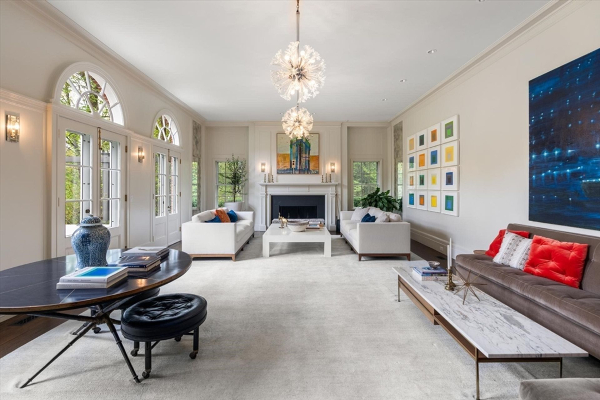 Living room exudes sophistication with its high ceilings, chic furnishings, and abundant natural light through arched French doors.