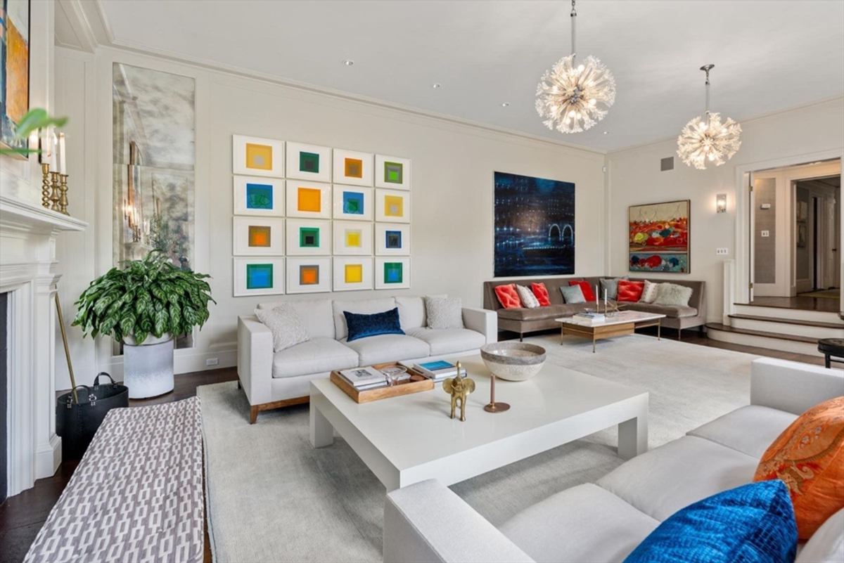 A modern living area features vibrant artwork, plush seating, and striking contemporary lighting that creates a bright and inviting atmosphere.