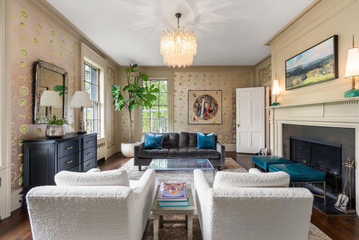 A refined sitting room combines modern accents, vibrant colors, and an ornate chandelier, creating a blend of classic and contemporary charm.