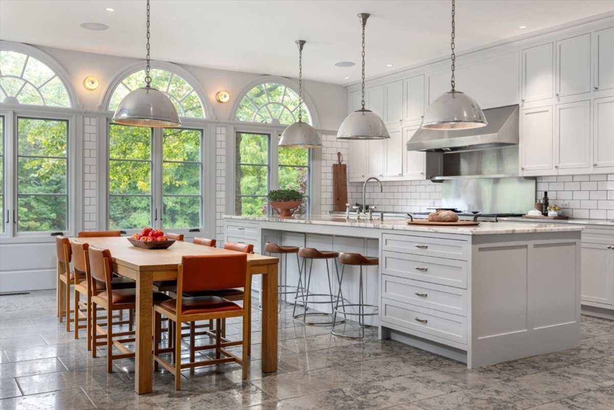 Dining space bathed in natural light from large arched windows offers serene views of the lush outdoors.