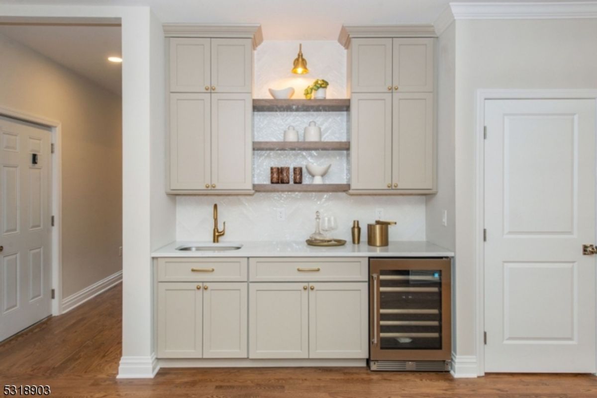 Compact beverage station features custom cabinetry, built-in wine cooler, and stylish shelving with ambient lighting.