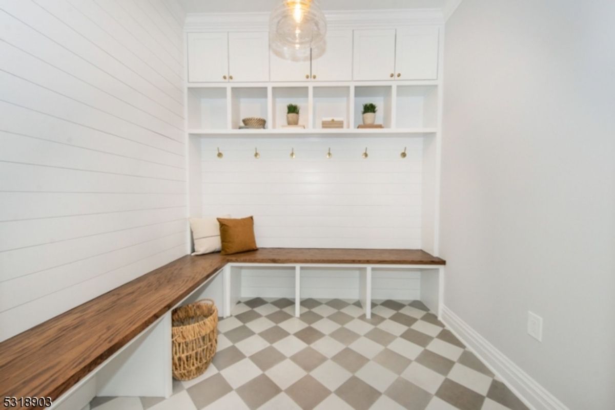 Charming mudroom showcases built-in cubbies, hooks, and bench seating with wood accents, complemented by checkerboard flooring.