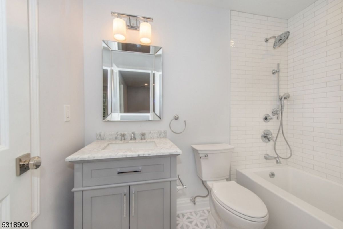 A stylish bathroom showcases a subway-tiled shower, a marble countertop vanity, and elegant fixtures for a contemporary touch.