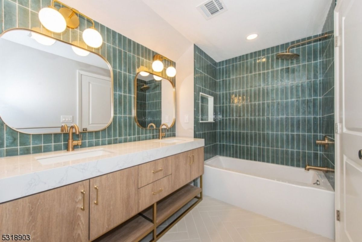 Bathroom showcases bold green tile walls, gold accents, and a modern floating double vanity for a stylish retreat.