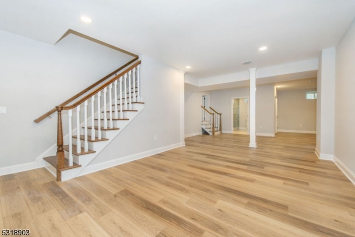 A spacious finished basement offers sleek flooring, neutral walls, and versatile open areas for customization.